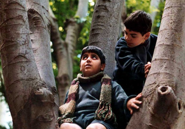 Mirco en een andere jongen zitten in een boom. Mirco kijkt naar de lucht, de andere jongen kijkt naar Mirco.