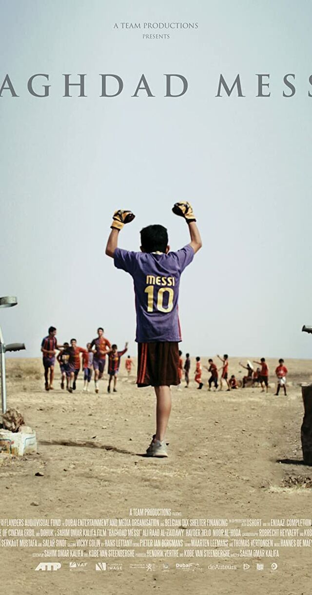 A boy with one leg in a Messi soccer jersey and goalkeeper gloves has his hands put up in the air. The rest of the team is running towards him.