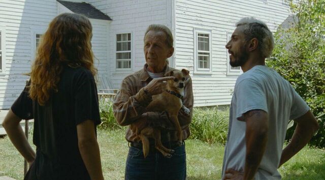 Ruben and Lou are talking to an elderly man with grey hair and a checkered shirt. He is holding a chihuahua.