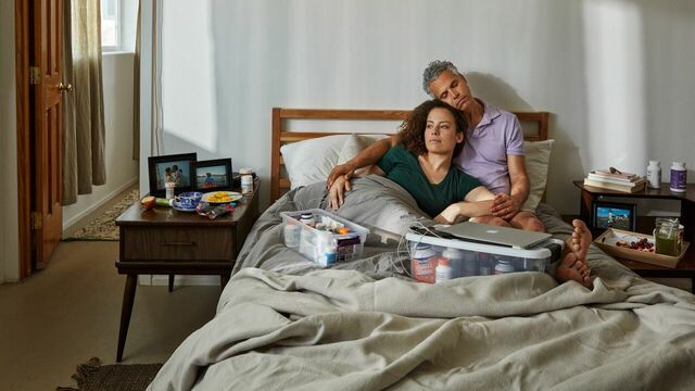 Jennifer en haar verloofde Omar liggen samen in bed. Naast hen staan twee plastic dozen met alle medicatie van Jennifer.