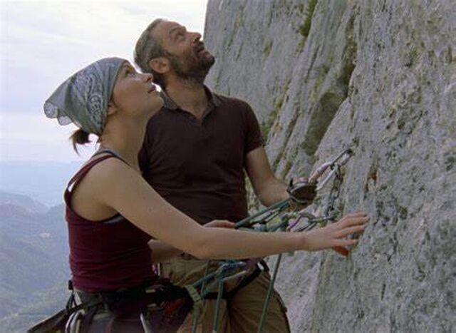 Een jonge vrouw en haar vader staan aan de voet van een rotswand. Ze kijken naar boven.