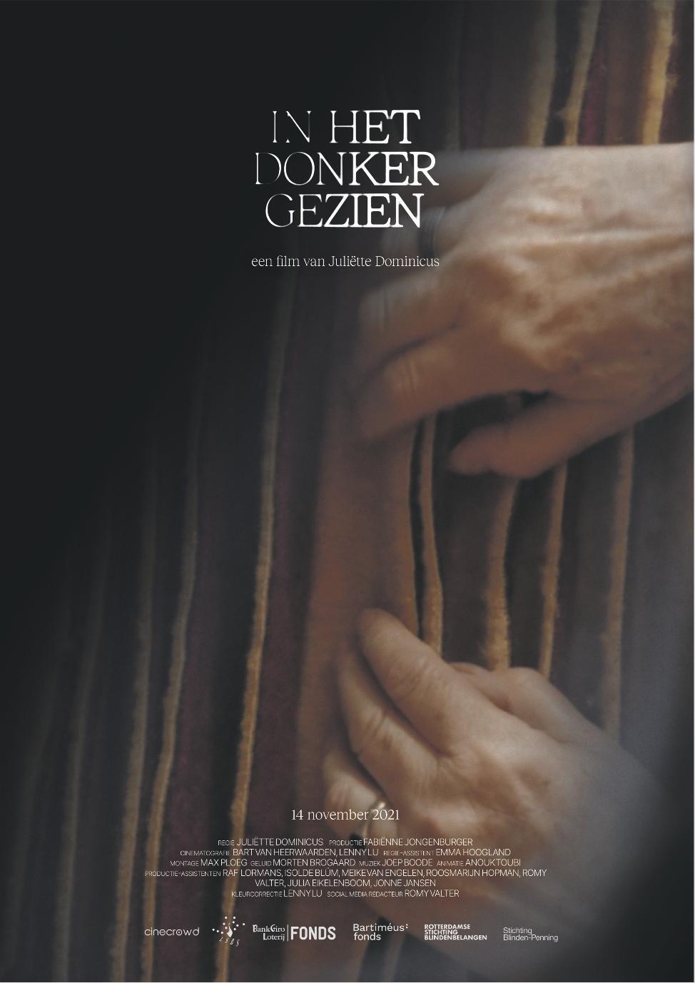 Poster van de film In het donker gezien Twee handen betasten een stuk stof met plooien